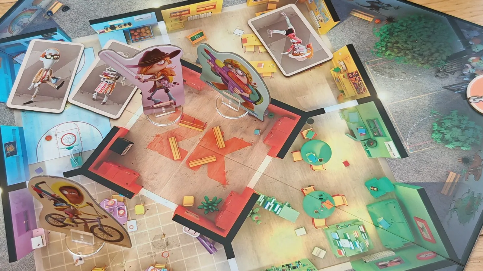 Aufgebautes Spielbrett von Zombie Kidz Evolution: die Schulräume mit drei Heldenfiguren und ausliegenden Zombie-Karten